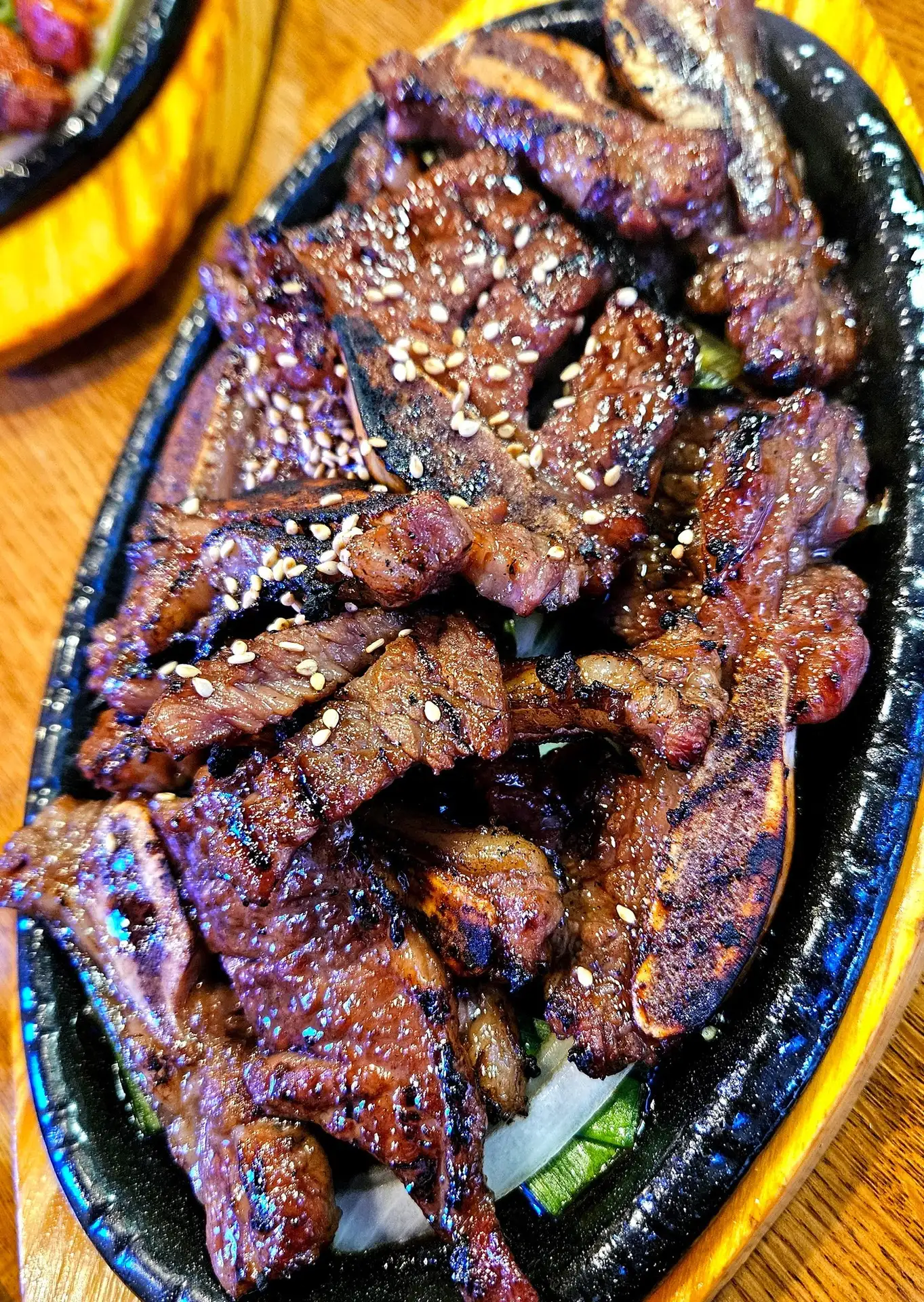 Chef JK Korean BBQ, Evans, GA: sizzling Korean BBQ galbi/bulgogi short ribs with grill marks and sesame seed garnish on a hot stone platter over lettuce