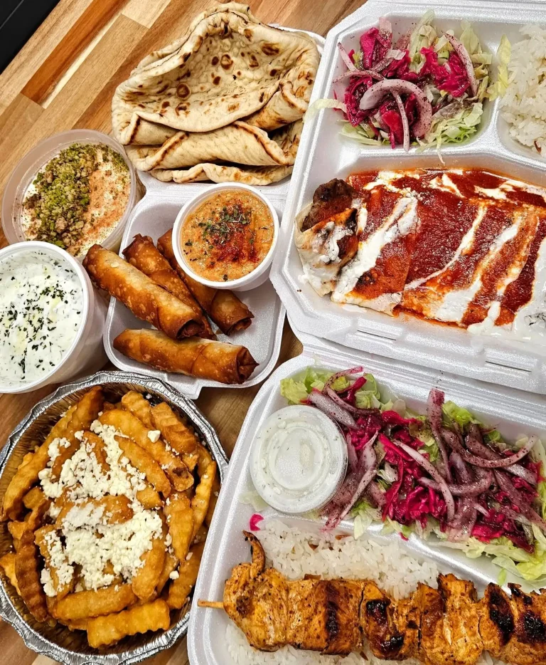 Shishkebab Restaurant, Evans, GA: mediterranean restaurant food spread in takeout containers: pita bread, hummus and tzatziki dips, fried spring rolls, feta fries, mixed salads with pickled onion, and grilled chicken/mea