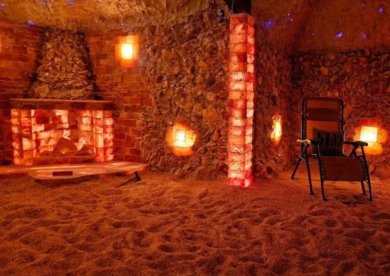 Sol Himalayan Salt Cave & Spa, Evans, GA: himalayan salt cave interior with glowing amber salt-brick walls and pillar, salt-crystal floor, cave-like stone ceiling, and a reclining zero-gravity chair for relaxation