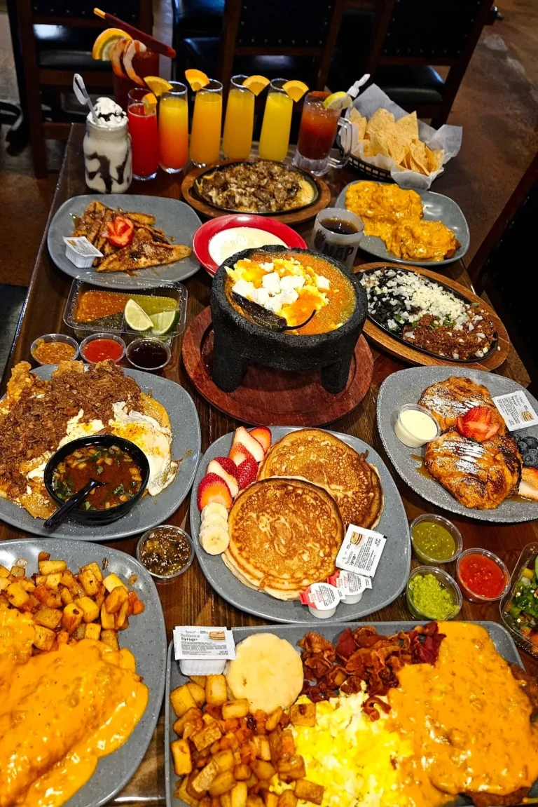 Taqueria El Rey, Augusta, GA: large Mexican breakfast/brunch spread: molcajete stone bowl dish, pancakes, home fries with queso, chilaquiles, huevos rancheros, tortilla chips, salsas, mimosas/juices lined up